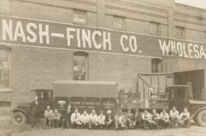 sepia tone photo of Nash-Finch Co. warehouse and workers sitting in front of a trick. 