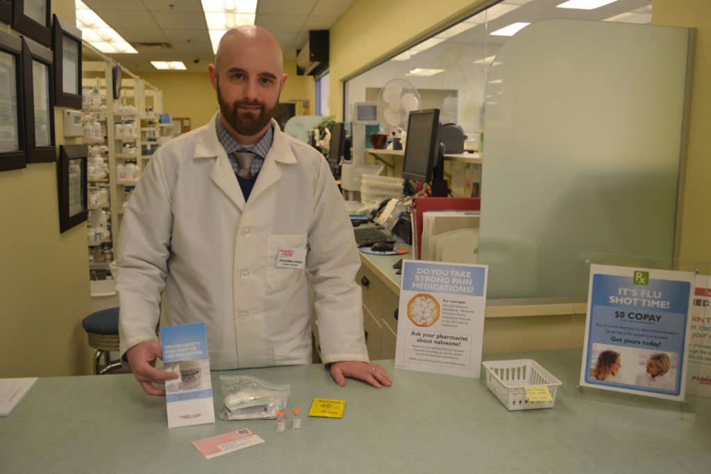 photo of Caucasian man in white lab coat holding a pamphlet