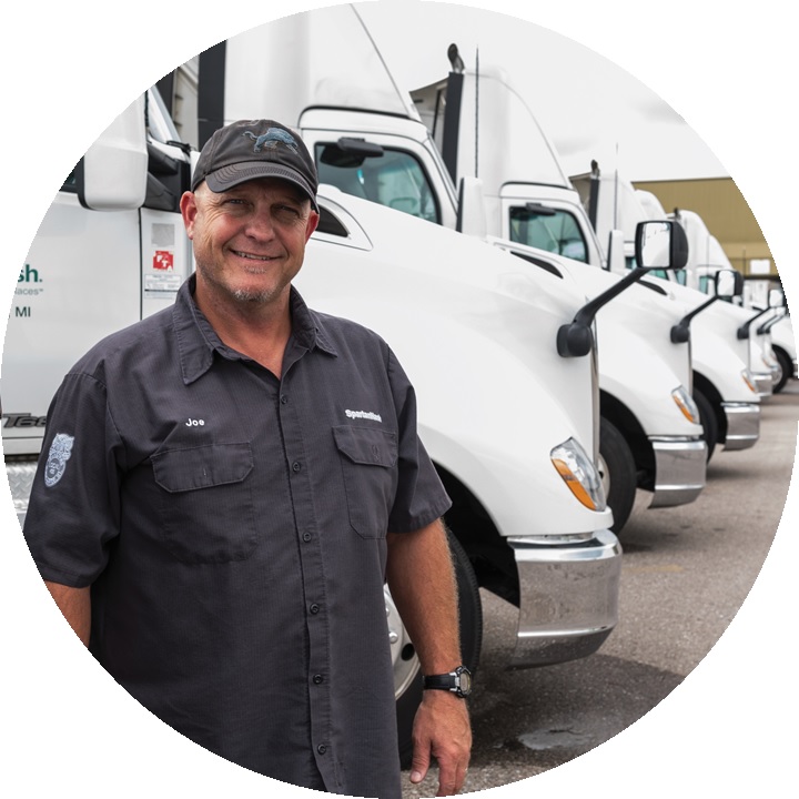 A driver standing in front of a fleet of semi-trucks