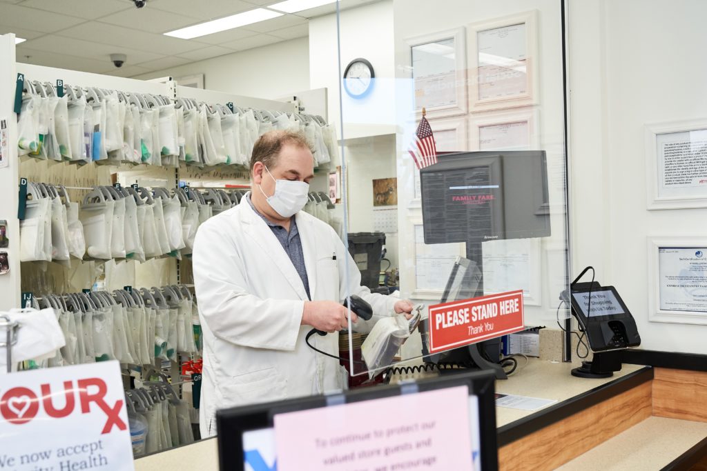 Pharmacy worker behind the counter, wearing medical masks