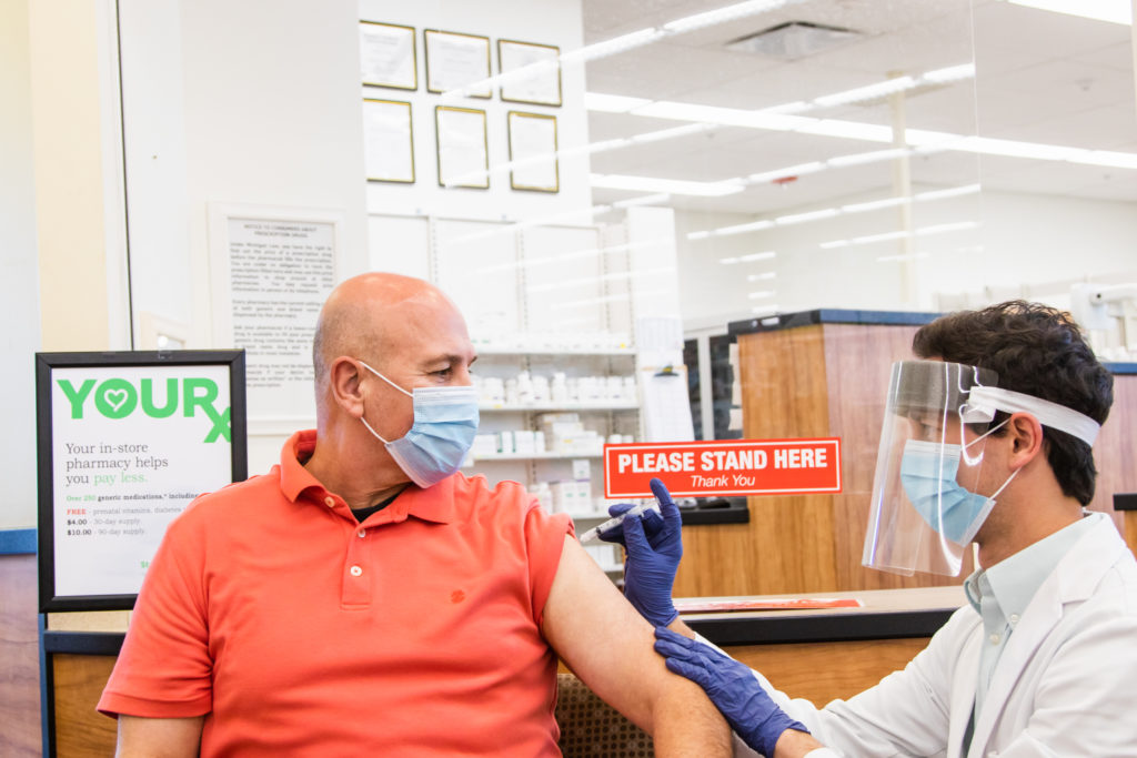 masked vaccination clinic worker administering vaccine to patient