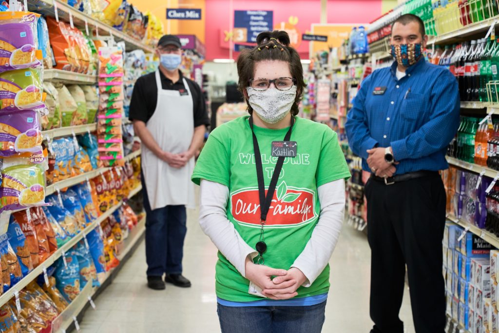 grocery story workers in medical masks standing in aisle at store