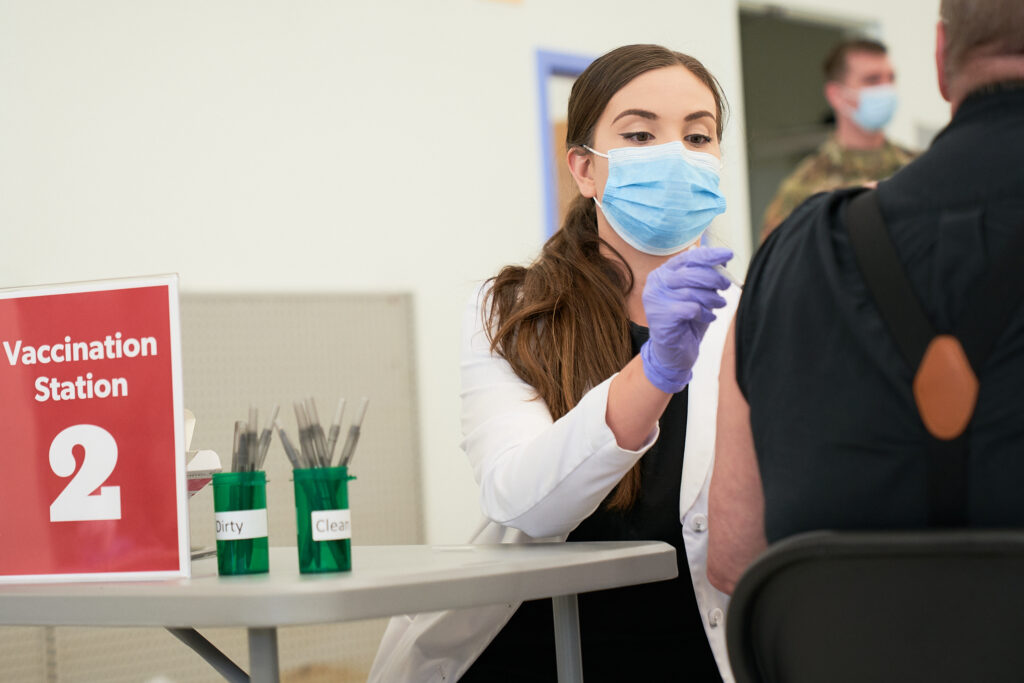 photo of vaccination clinic worker giving vaccine to a man