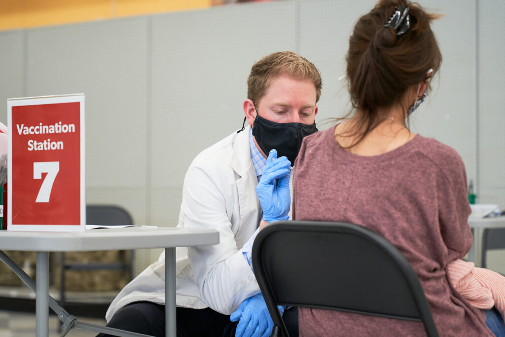 photo of a worker at a vaccination clinic giving a vaccine to a woman
