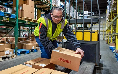 Wholesale Food Distribution | a man loading boxes on a forklift pallet